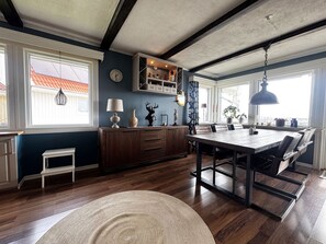 A spacious kitchen with a wooden dining table, a built-in oven, and a window overlooking a red-roofed building. - Holiday home in beautiful Kungshamn – perfect for two families | SE09079 (Kungshamn)