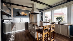 A kitchen with a central island, wooden chairs, and a window with a view.