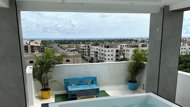 A rooftop terrace with a hot tub, seating area, and potted plants.