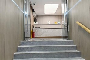 A staircase leading to a modern kitchen area with marble countertops and a wooden wall.