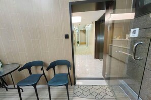 A hotel room entrance with a glass door, a small table with chairs, and a tiled floor. - Huamin Hotel (Huashan Hospital Hotel Jiangsu Road Shanghai) (Shanghai)