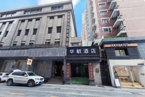 A hotel with a modern facade, a visible entrance, and a sign for a Pilates studio. - Huamin Hotel (Huashan Hospital Hotel Jiangsu Road Shanghai) (Shanghai)