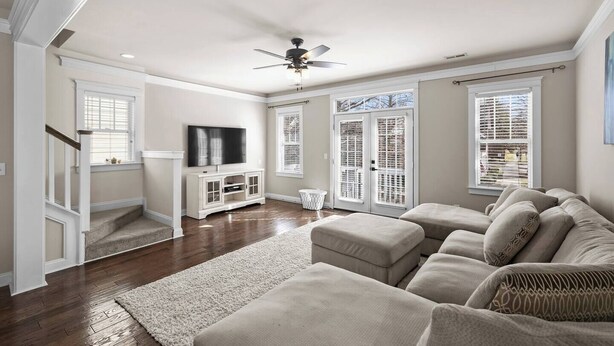 A spacious living room with a sectional sofa, a flat-screen TV, and a ceiling fan. - Charming Uptown Charlotte Oasis with En Suites & Balcony with quiet street, walk to coffee shops nearby and minutes to convention center and uptown offices. (Charlotte)