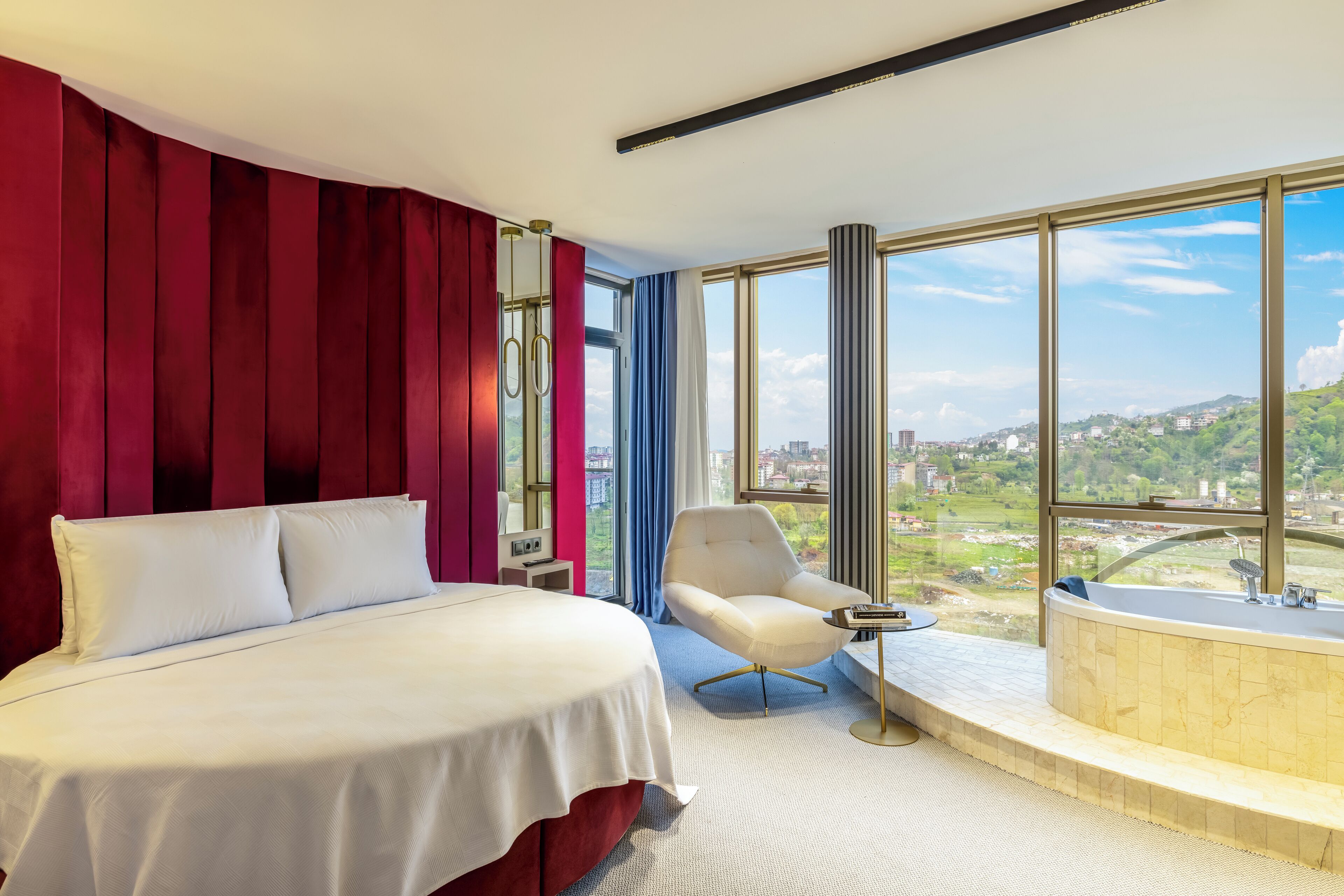 Una habitación de hotel con una cama grande, una zona de estar con vistas y una bañera.