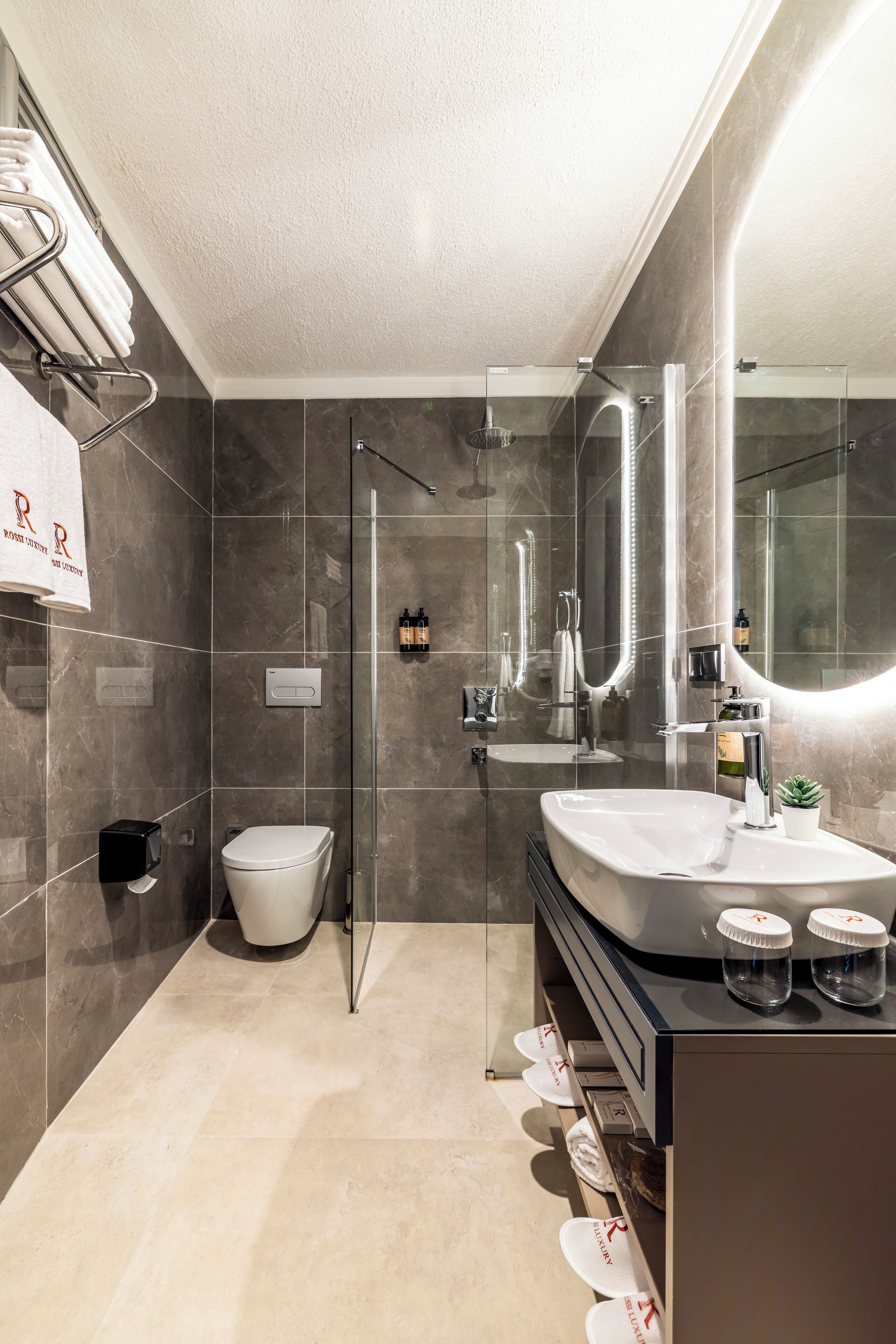 A modern bathroom with a glass-enclosed shower, a large vanity with a mirror, and a toilet.