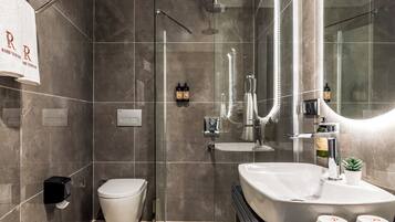 A modern bathroom with a glass-enclosed shower, a large vanity with a mirror, and a toilet.