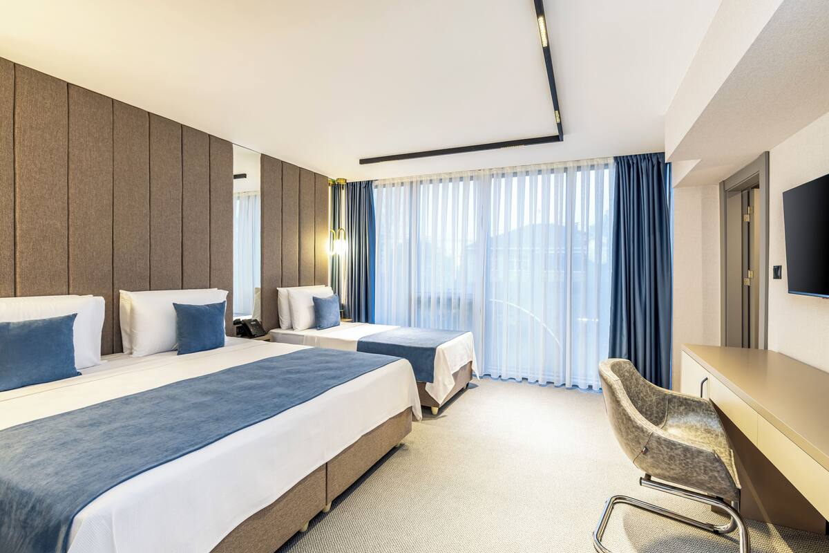 Ett hotellrum med två sängar, ett skrivbord och en stol.