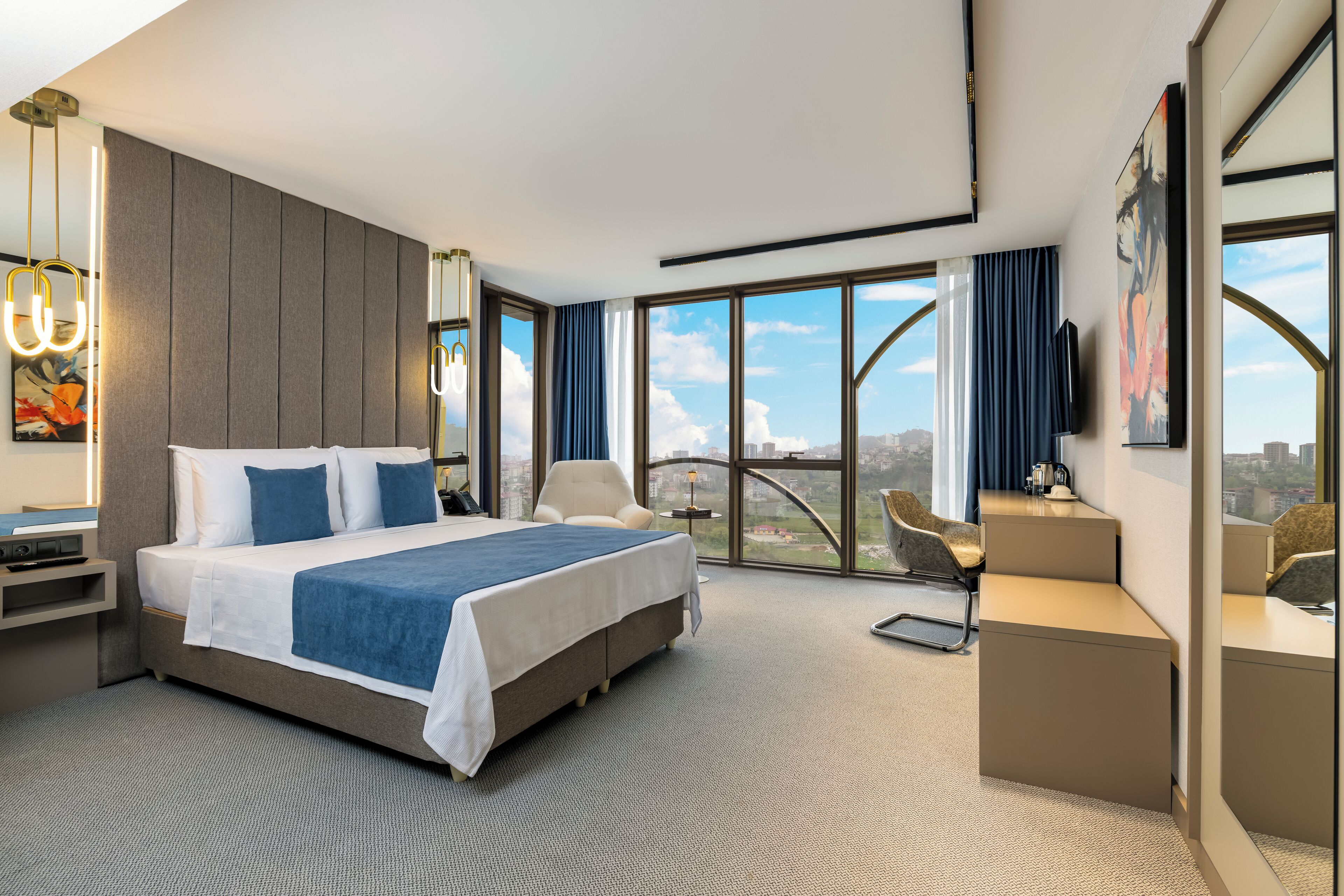 Quarto de hotel moderno com uma cama grande, uma escrivaninha e vista para a cidade.
