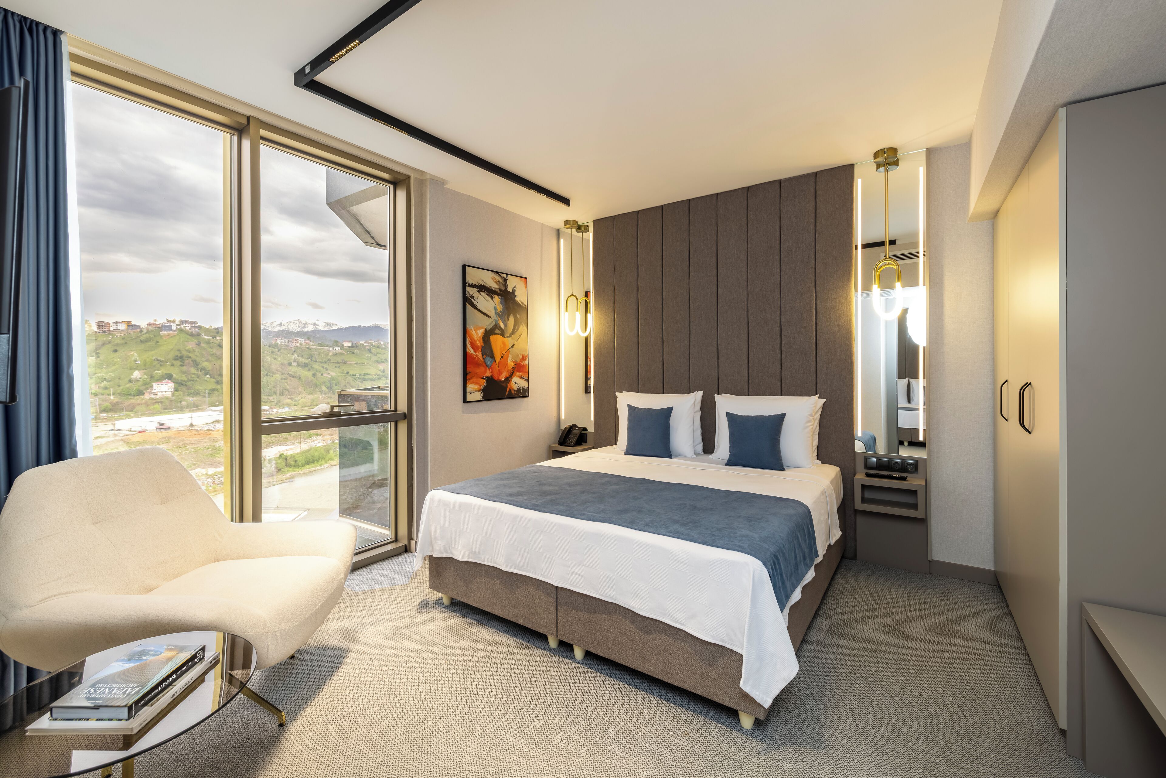 Una habitación de hotel moderna con una cama grande, una zona de estar y vistas a un paisaje urbano.