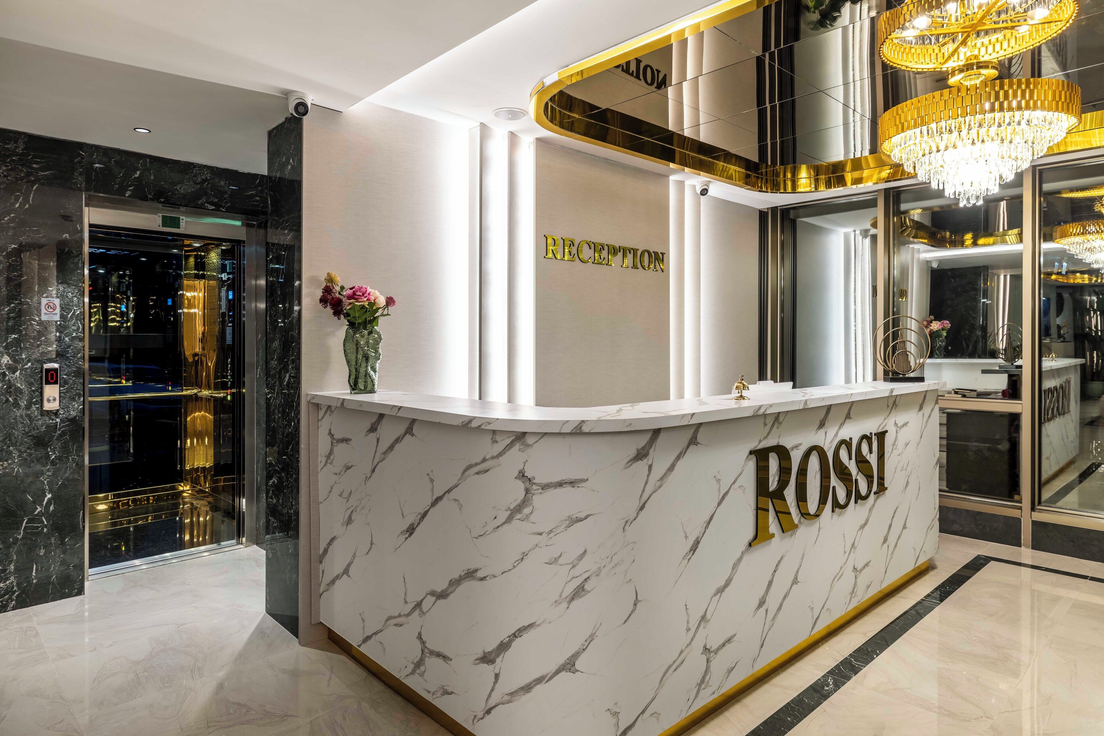 Una reception con piano in marmo e la scritta 'ROSSI' in caratteri dorati.