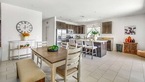 Une cuisine moderne dotée d’un îlot central, de meubles blancs et d’appareils électroménagers en acier inoxydable.