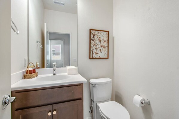 A bathroom with a white sink, a toilet, and a framed artwork on the wall. - Indio Wordsworth - Pool, BBQ, Games, Fire Pit (Indio)