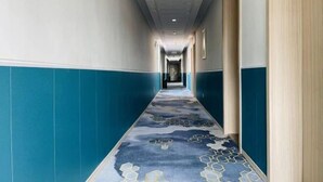 A long hallway with blue and white walls, a patterned carpet, and a ceiling with recessed lighting. - Tianyue Hotel (Shangqiu Ancient City First People's Hospital) (Shangqiu)