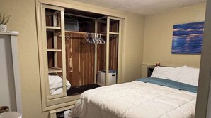 Una camera da letto con un letto, un armadio con ante in legno, una finestra e un quadro appeso al muro.