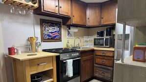 Una cucina compatta con mobili in legno, un fornello, un microonde e un frigorifero.