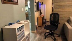 Una stanza con parete in legno, una scrivania con computer, una sedia e un televisore appeso al muro.