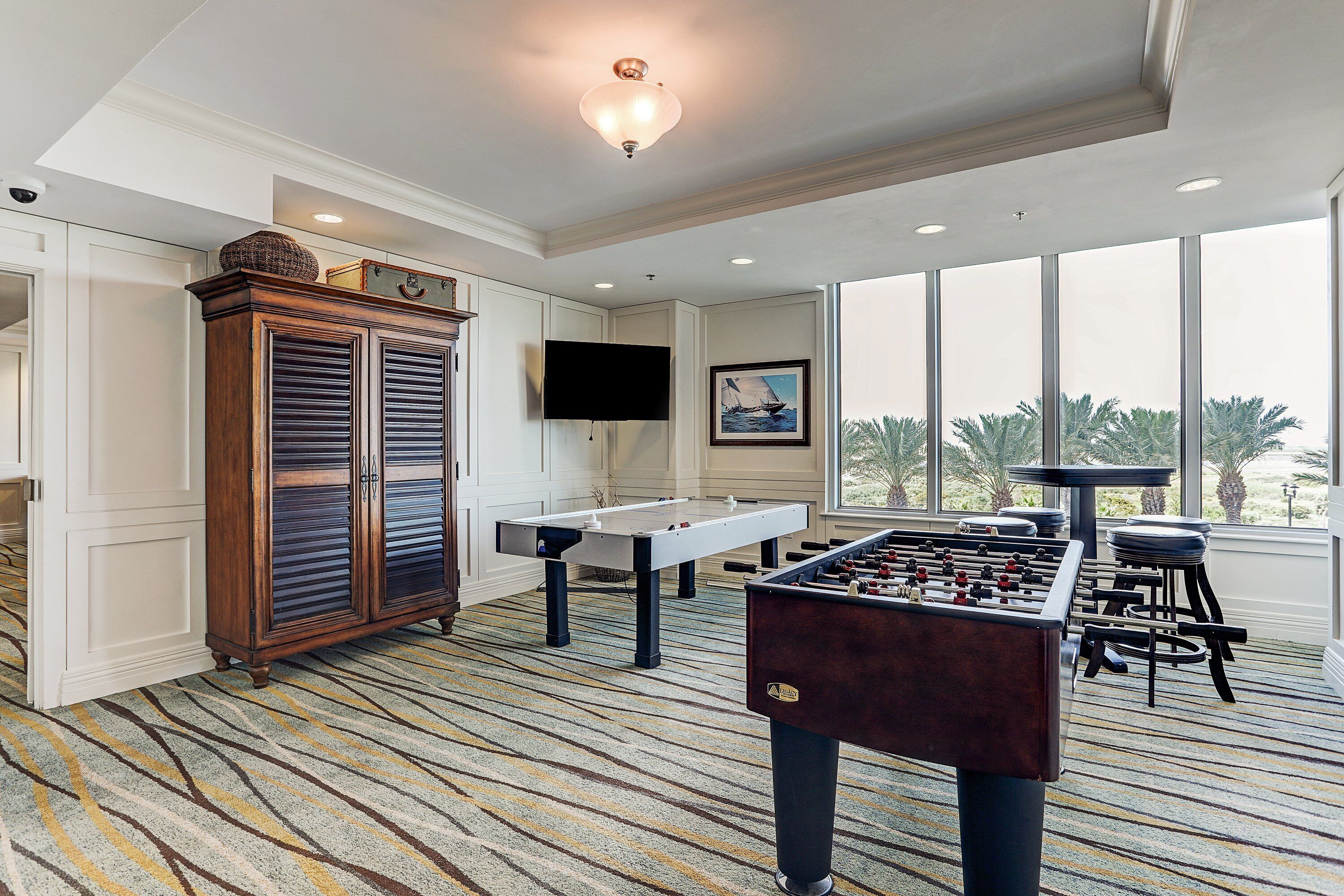 Une pièce spacieuse équipée d’un baby-foot, d’une table de billard et d’une grande armoire.