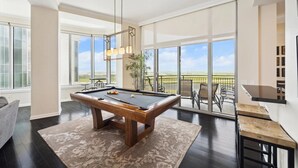 A spacious room with a pool table, large windows, and a view of the landscape.