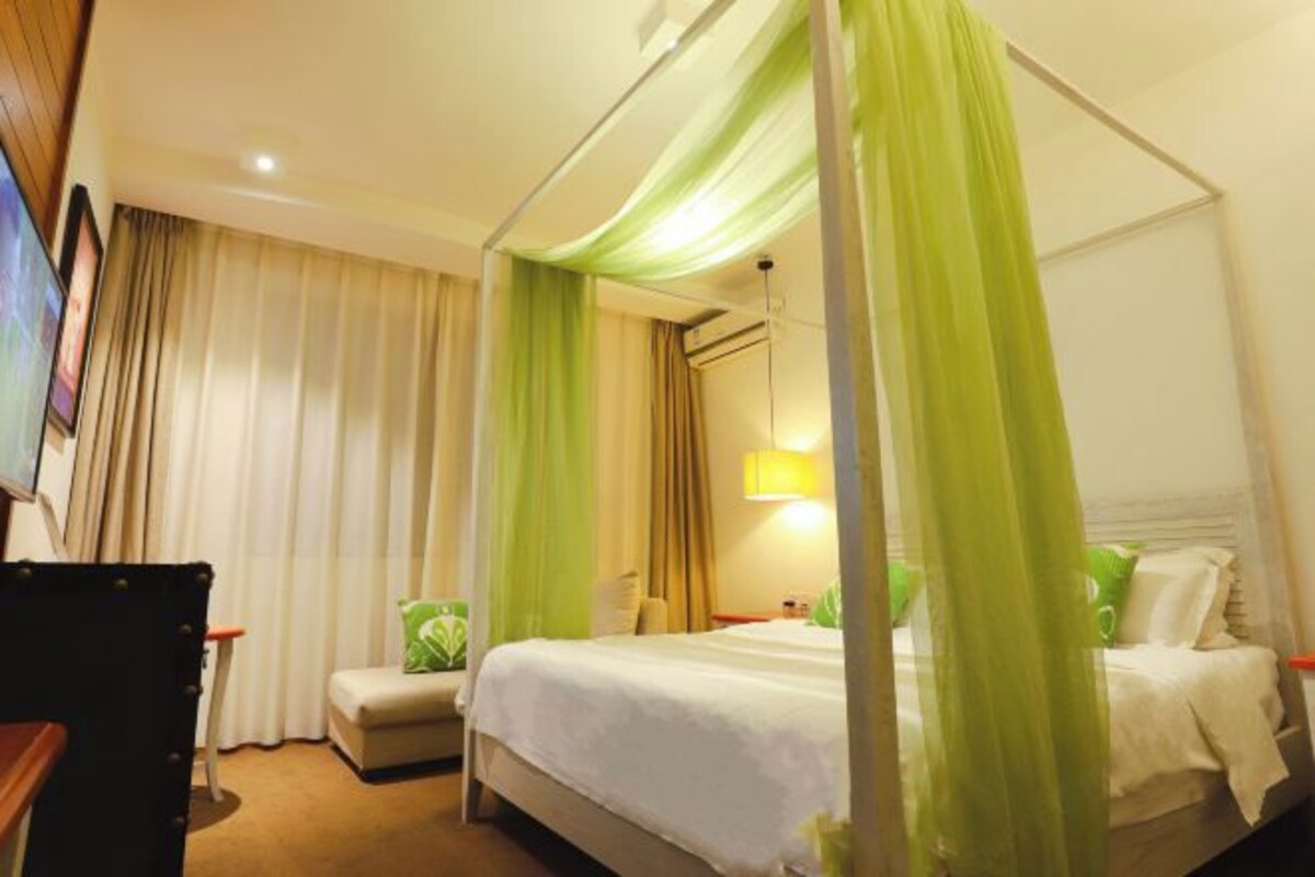 A hotel room with a bed, a chair, a desk, and a TV.