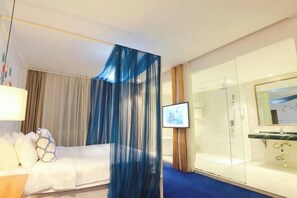A hotel room with a bed, a TV, a glass shower, and a bathroom with a mirror. - Huangjia Qiangui Business Hotel (Zibo)