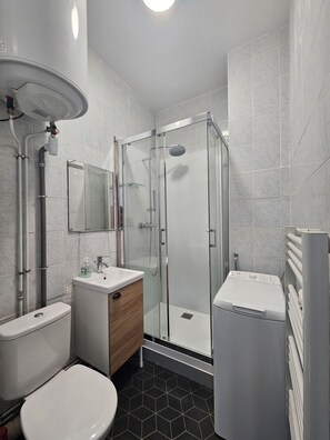Een douche, handdoeken, zeep, toiletpapier