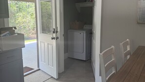Una cocina con refrigerador, una mesa de comedor de madera y una puerta que da a un área de lavandería.