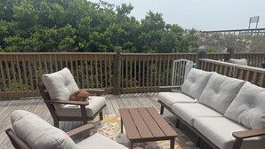 Une terrasse avec un canapé, deux fauteuils et une petite table.
