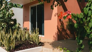 A modern house with a large glass door, surrounded by various plants and flowers. - Maralagua (Puerto Escondido)