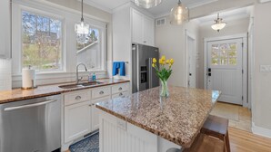 Een moderne keuken met granieten aanrechtbladen, roestvrijstalen apparatuur en hanglampen.