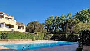 Une piscine à bordures courbes, entourée d’une terrasse dallée.