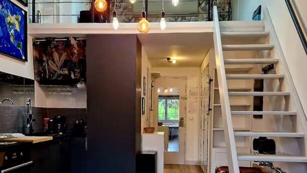 Une cuisine moderne dotée d’un îlot central, d’un escalier menant à un étage supérieur et offrant une vue sur l’extérieur.