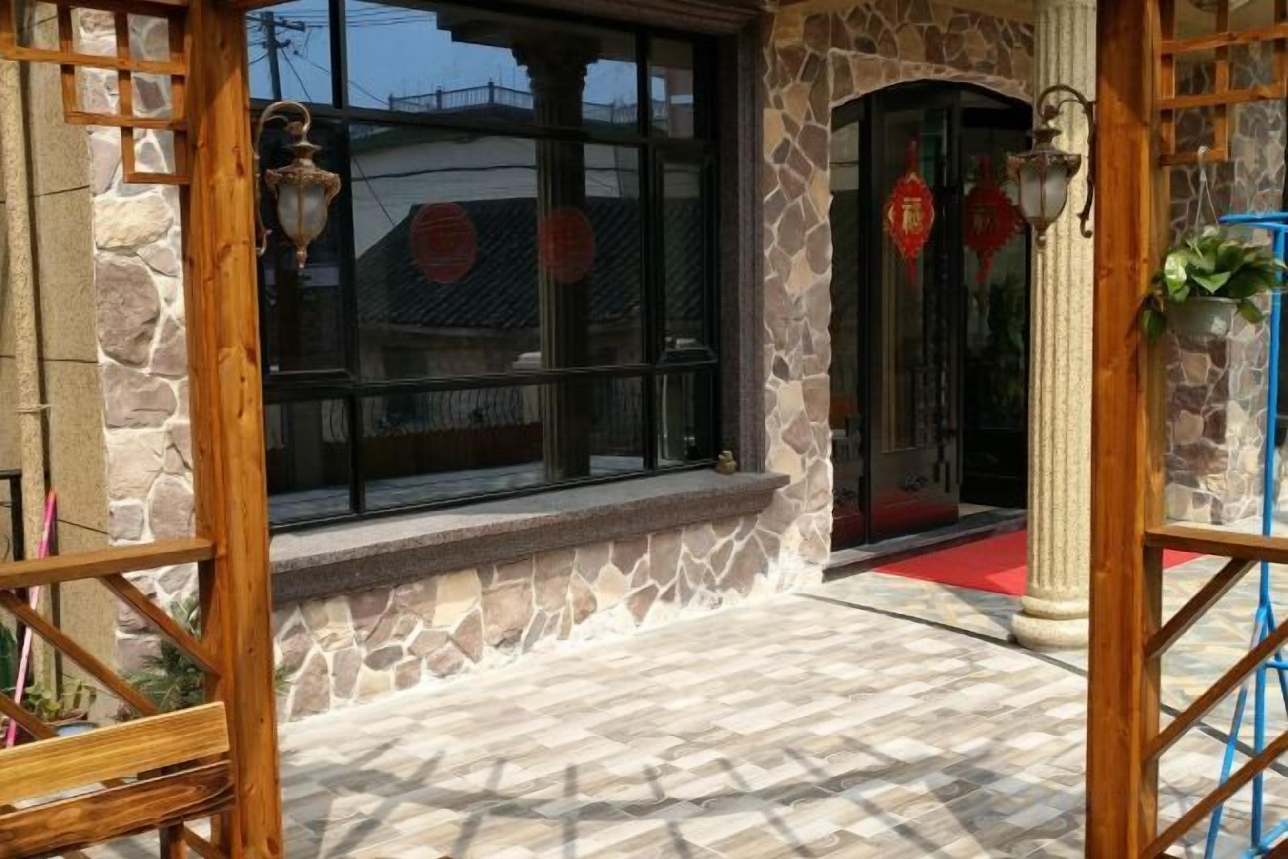 A stone building entrance with a red carpet, a window with a view, and a door with a red decoration.