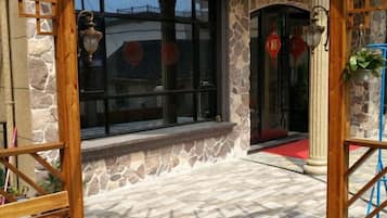A stone building entrance with a red carpet, a window with a view, and a door with a red decoration.