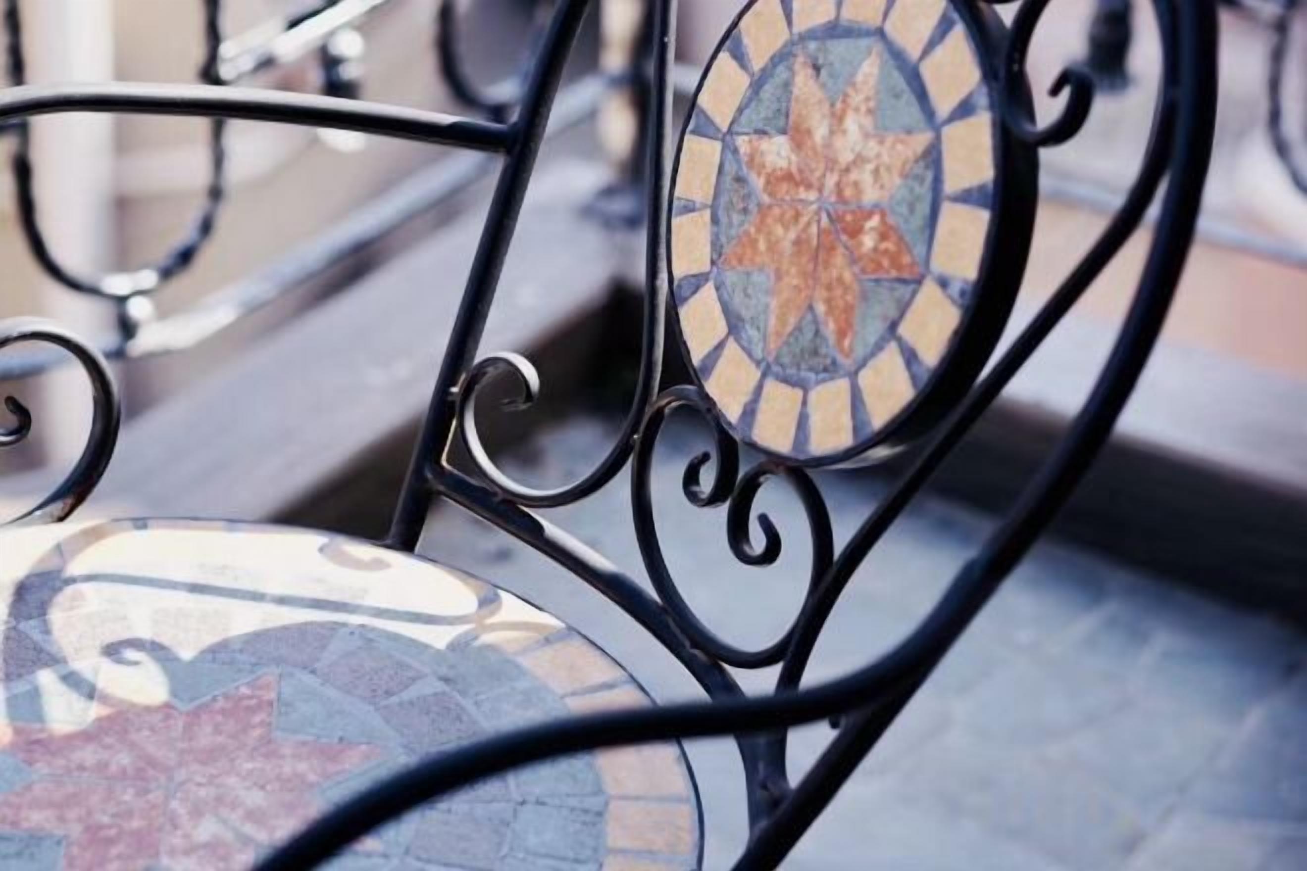 A metal chair with a mosaic design on the backrest.