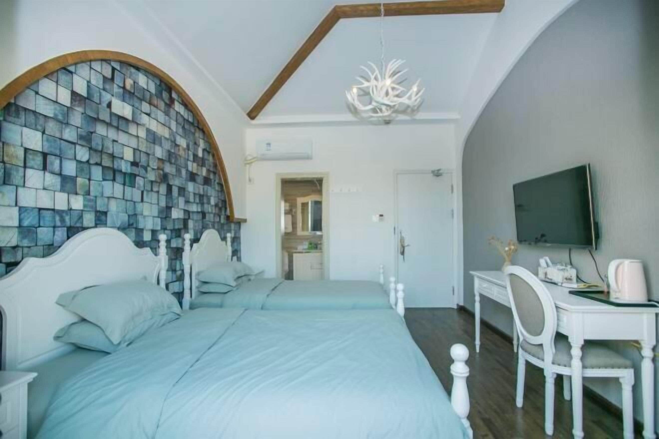 Een slaapkamer met een groot bed, een bureau, een televisie en een unieke mozaïekwand.