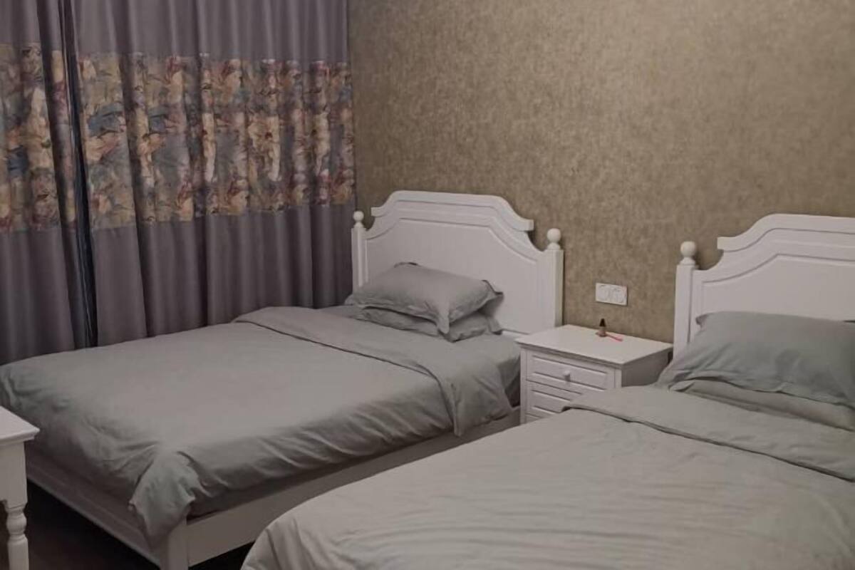 Quarto com duas camas, uma mesa de cabeceira e um relógio na parede.