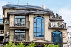 Un edificio de dos pisos con balcones, ventanas amplias y una chimenea.