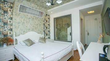 A bedroom with a bed, a desk, and a large window.