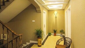 A hallway with a wooden staircase, potted plants, and a wall-mounted deer head decoration. - Fallen Bay (Shengsi)