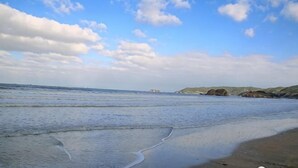 A beach with calm water, distant hills, and a partly cloudy sky. - Fallen Bay (Shengsi)