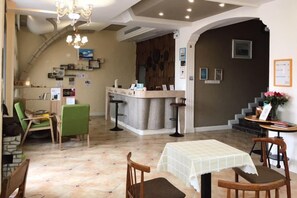 A restaurant with a bar area, a dining table, and chairs. There is a staircase leading to an upper level. - Fallen Bay (Shengsi)