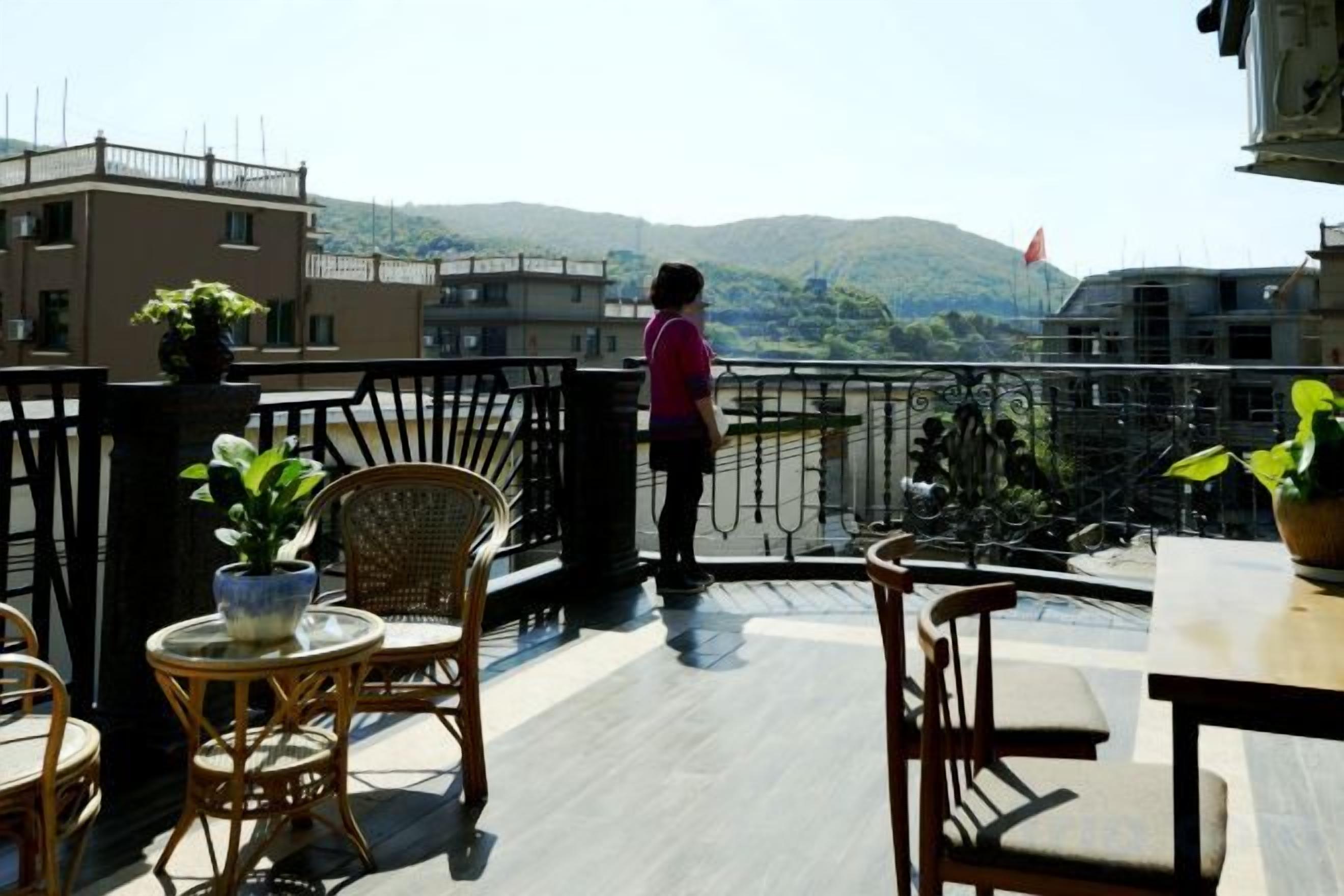 A balcony with wicker furniture, a potted plant, and a view of a mountain.