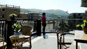 A balcony with wicker furniture, a potted plant, and a view of a mountain.