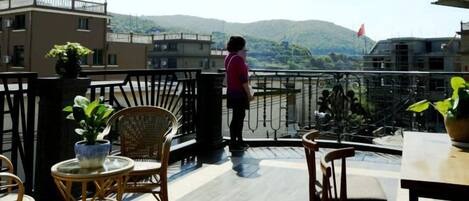 A balcony with wicker furniture, a potted plant, and a view of a mountain.