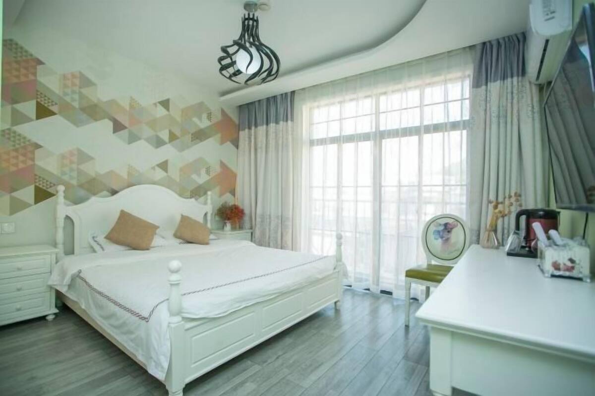 Um quarto com cama, mesa de cabeceira e escrivaninha com cadeira.