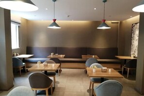 Ein Restaurant mit Sitzecken, Tischen und hängenden Pendelleuchten.