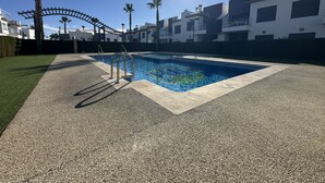 A swimming pool with a metal ladder, surrounded by a pebble-tiled deck and palm trees. - Casa Blanca (Pilar de la Horadada) (Pilar de la Horadada)