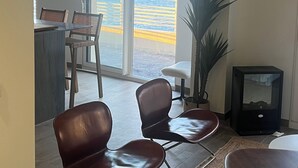 Una habitación con vista al océano, un área de comedor con sillas, una mesa y una planta en maceta.