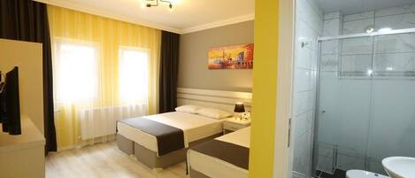 A hotel room with two beds, a bathroom with a glass shower, and a painting on the wall.