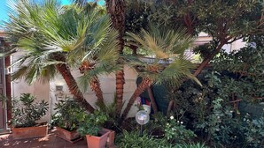 A tiled patio with potted plants and a small garden area. - MONDELLO COTTAGE ULIVO 1 | Beach Apartment with Private Garden & Parking (Palermo)